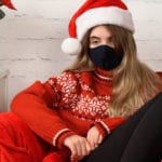 Woman dressed for Christmas wearing face mask looking sad