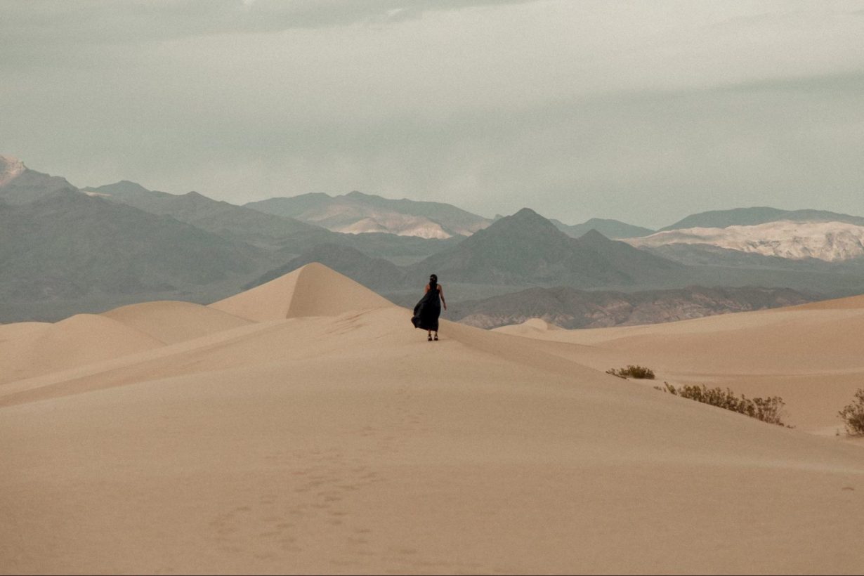 Quina Aragon walking away on a sand dune. 