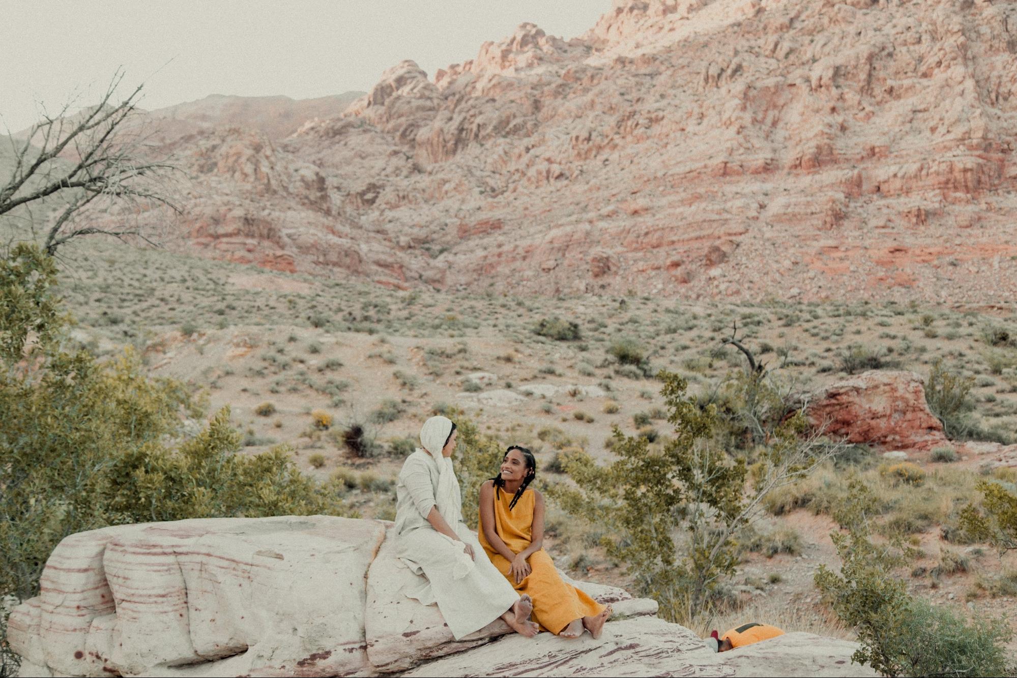 Quina Aragon and Karen Ellis sitting on a rock in the desert. 