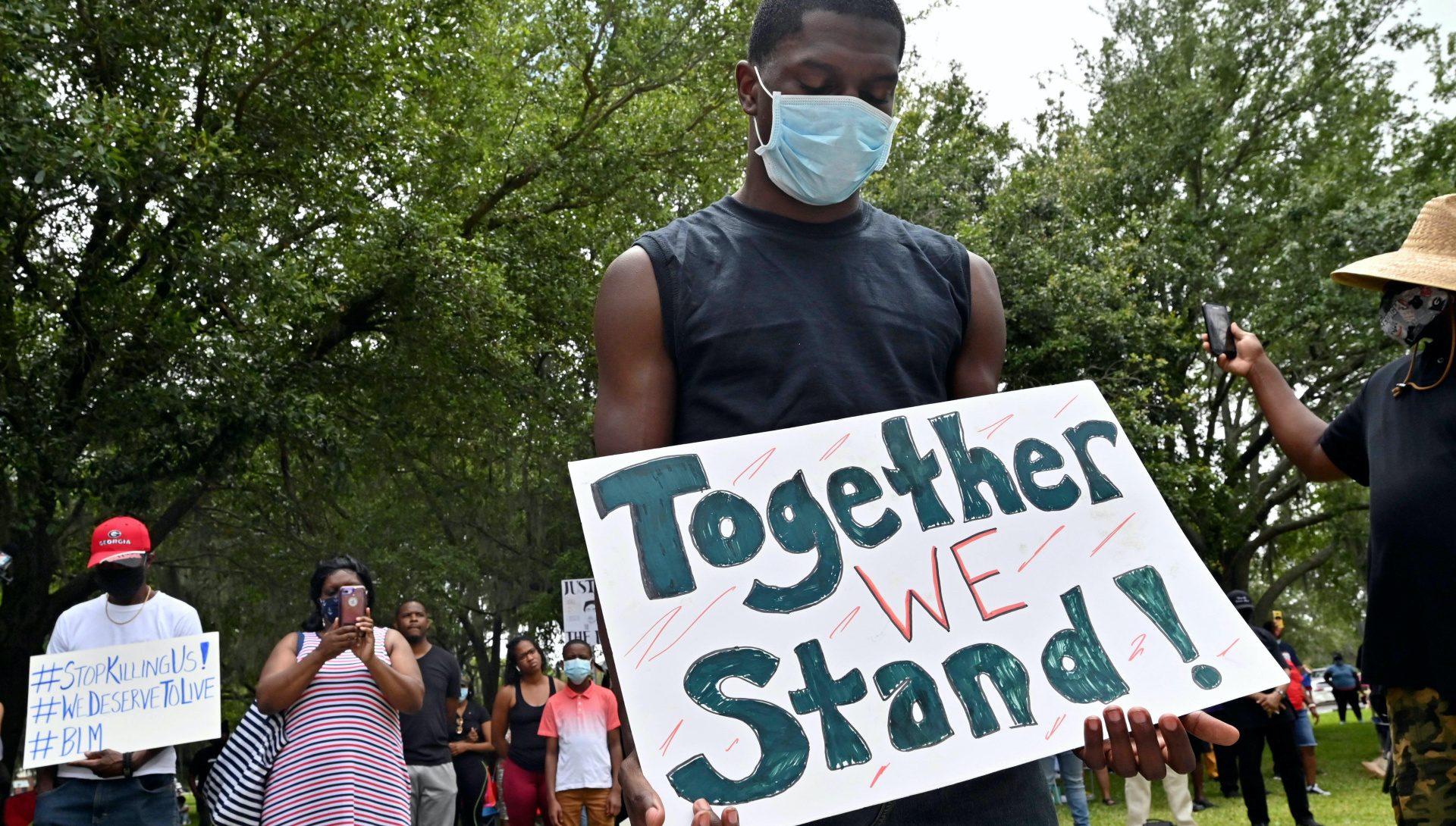 Man holding Together We Stand sign at a peaceful protest