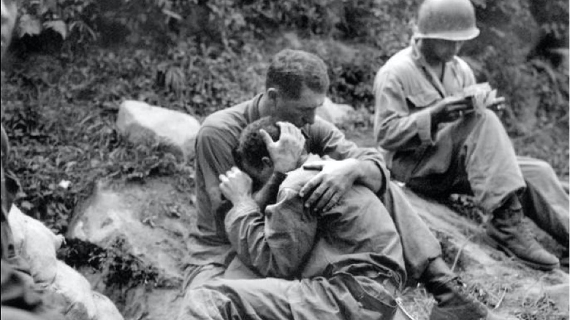 Soldiers in battle comforting one another