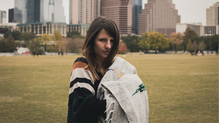 Homeless woman hold a blanket in the city