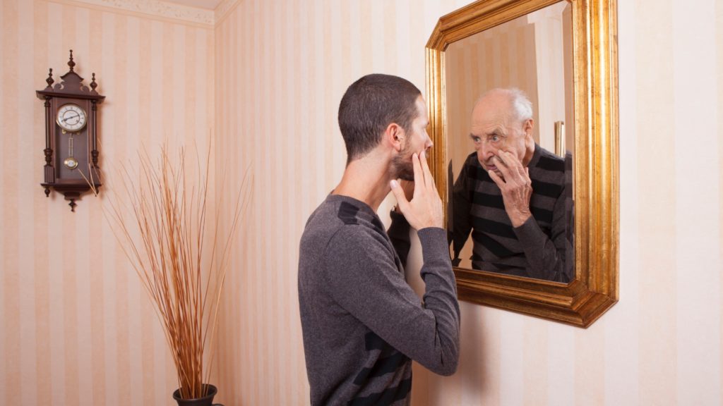 man looking at older self