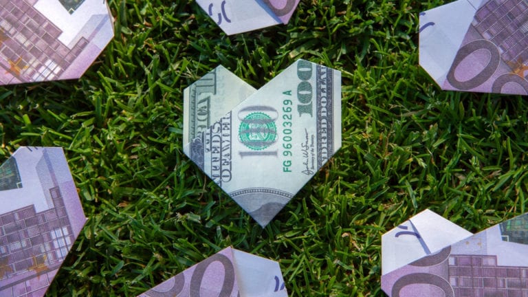 What's Wrong with the Prosperity Gospel? Dollars folded into hearts on grass