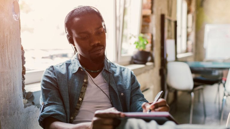 African man listening to a sermon and taking notes in a cafe