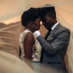 Healthy sex - an African married couple together inside a veil embracing