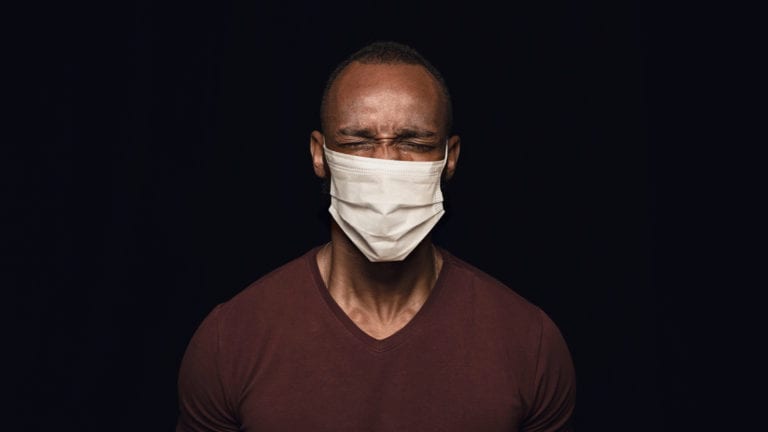 Empty, Alone, Desperate - African man in protective mask looking distressed - black background