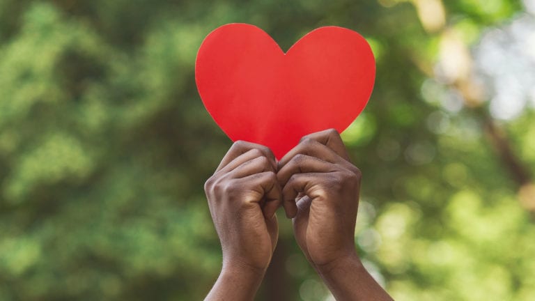 Should I Tithe or is it more about being generous? African hands holding up a red paper heart.