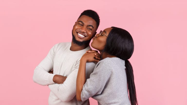 To far? Physical affection while dating - African couple almost kissing on a pink background