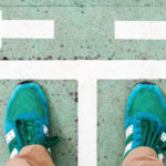 Which Career path? Person looking down on their green sneakers with arrows painted on the floor