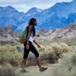 Living As Strangers- A woman walking through mountains.