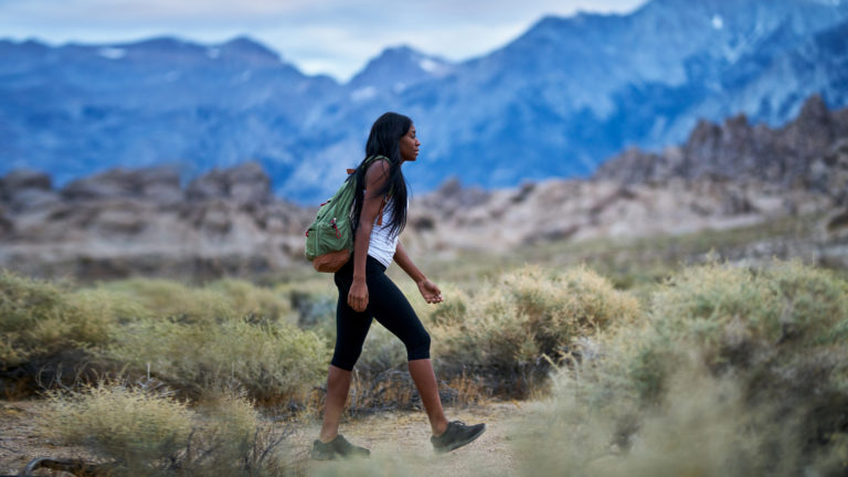 Living As Strangers- A woman walking through mountains.