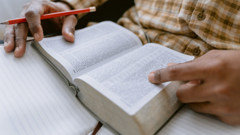 Apostle Paul's instructions for Tongues - Person with Bible on lap going through scripture with notebook and pencil