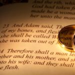 Biblical Marriage - Two rings on top of the a page in the bible in the book of Genesis