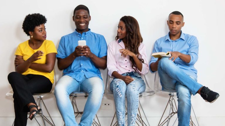 Job interview tips- Young people sitting on chairs talking to each other.