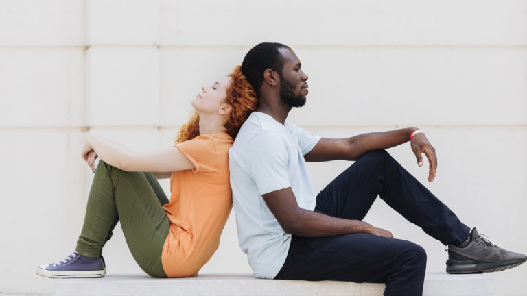 Interracial Relationships - Guy and girl sitting back to back.