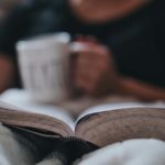 Bible reading - A person sitting in bed with a cup of coffee and their bible.