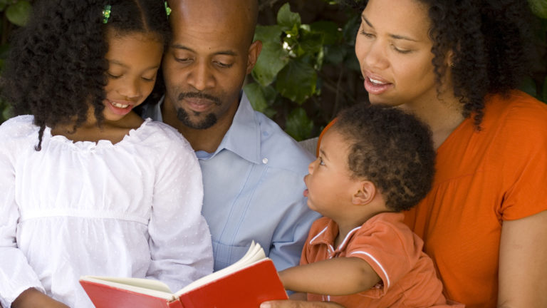 Family Devotions - A family sitting together reading a book.