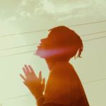 Sin - A guy standing with eyes closed and hands together as if to pray.