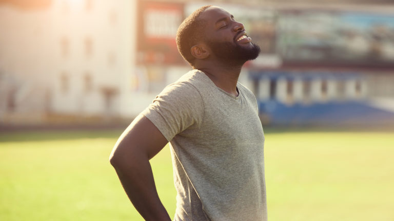 Delighting in the sabbath - A man standing in nature looking up, smiling with eyes closed