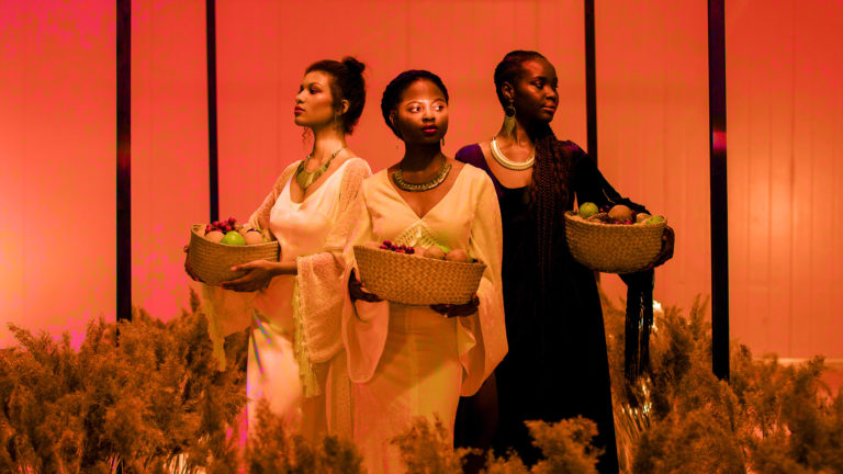 Polygamy - Three women standing next to each other holding fruit baskets.