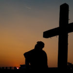 Grace - A guy sitting at a wooden cross