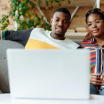 Streaming church services - A couple sitting on their couch, watching something on their laptop