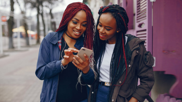 Top four articles from four years - Two women walking down the street looking at phone.