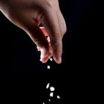 Being salt and light - A hand sprinkling salt on a black background