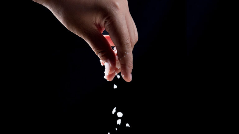 Being salt and light - A hand sprinkling salt on a black background