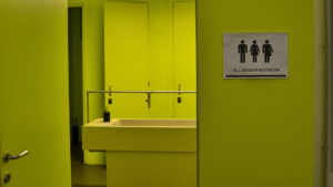 Gender - A green bathroom door with 3 gender symbols on it