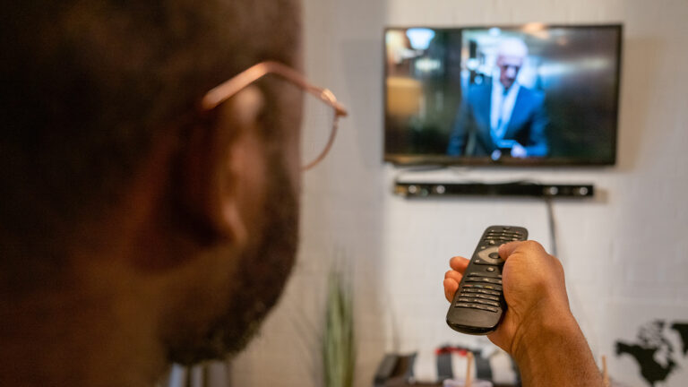 Binge Waching - A guy holding a remote pointing it at the tv