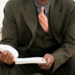 Preaching theology – A man sitting on a step outside reading the bible.