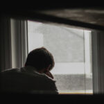 Healing – A guy sitting on his bed looking down