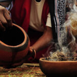 Ancestral Worship – A woman with a bowl in her hand pouring contents into a burning bowl of incense.