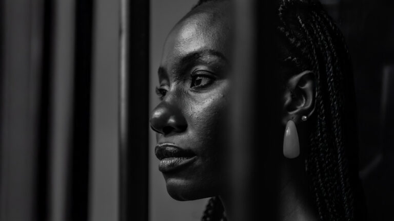 Singleness – A woman standing behind bars looking out into the distance