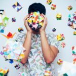 An image of a guy holding a colour 3 D object to is face.
