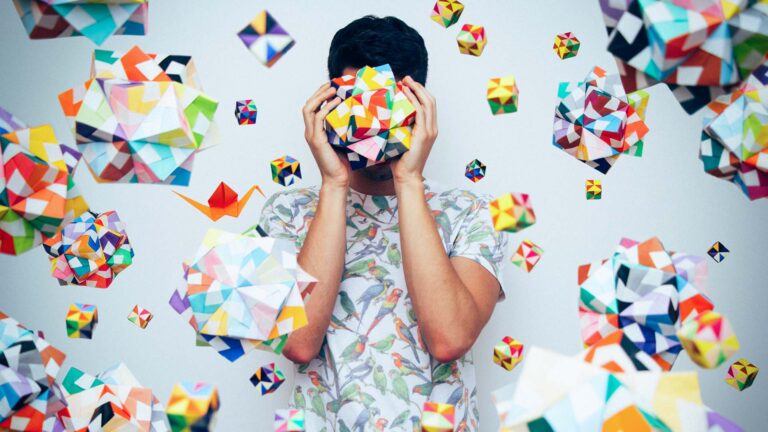 An image of a guy holding a colour 3 D object to is face.